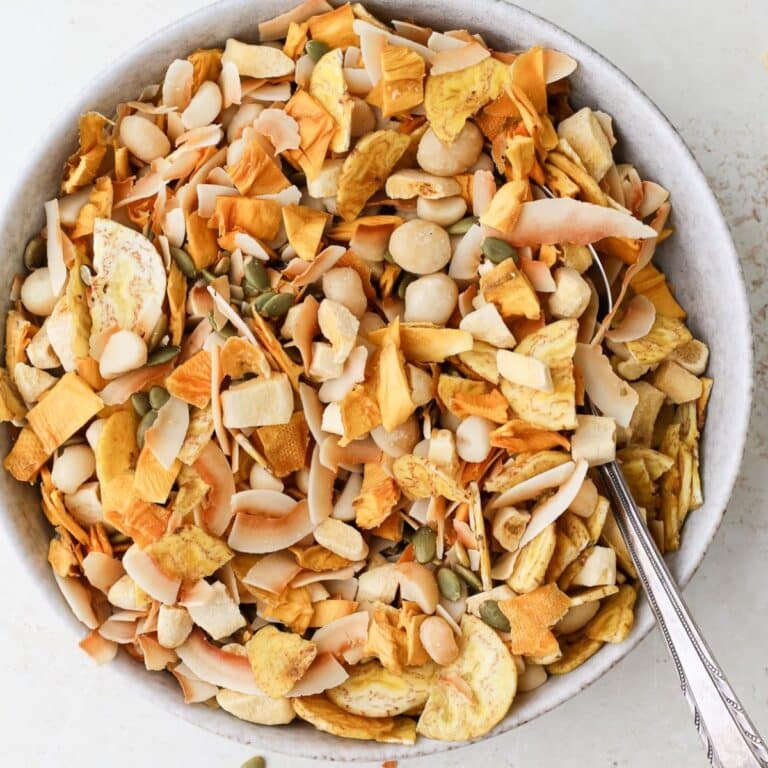 Mixed tropical trail mix in a large bowl with a spoon.