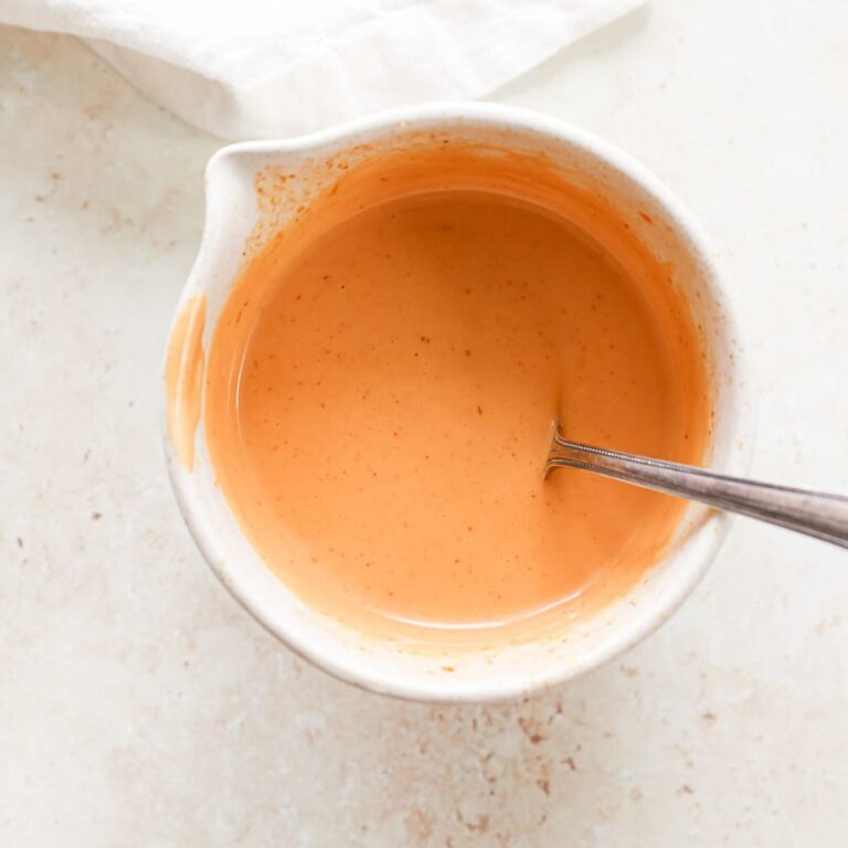 A bowl of homemade orange Japanese spicy mayo with a spoon.