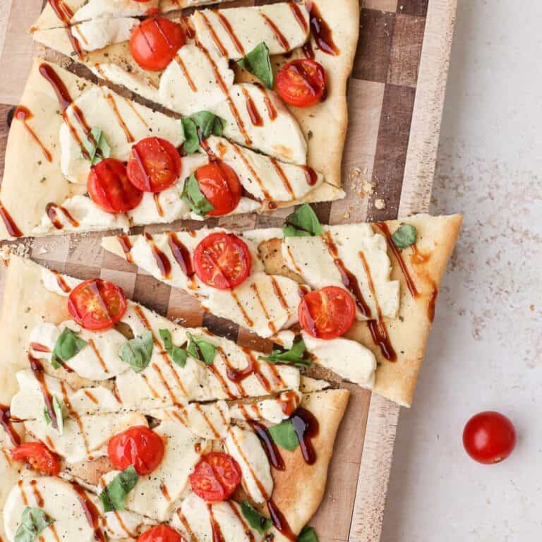 A caprese flatbread with cherry tomatoes and dairy free mozzarella and drizzle of balsamic glaze.