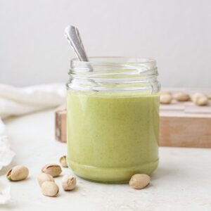 A jar of homemade pistachio cream with a spoon.