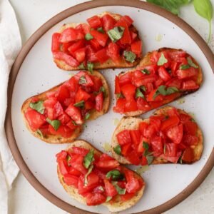 Bruschetta al pomodoro with fresh basil on a plate.