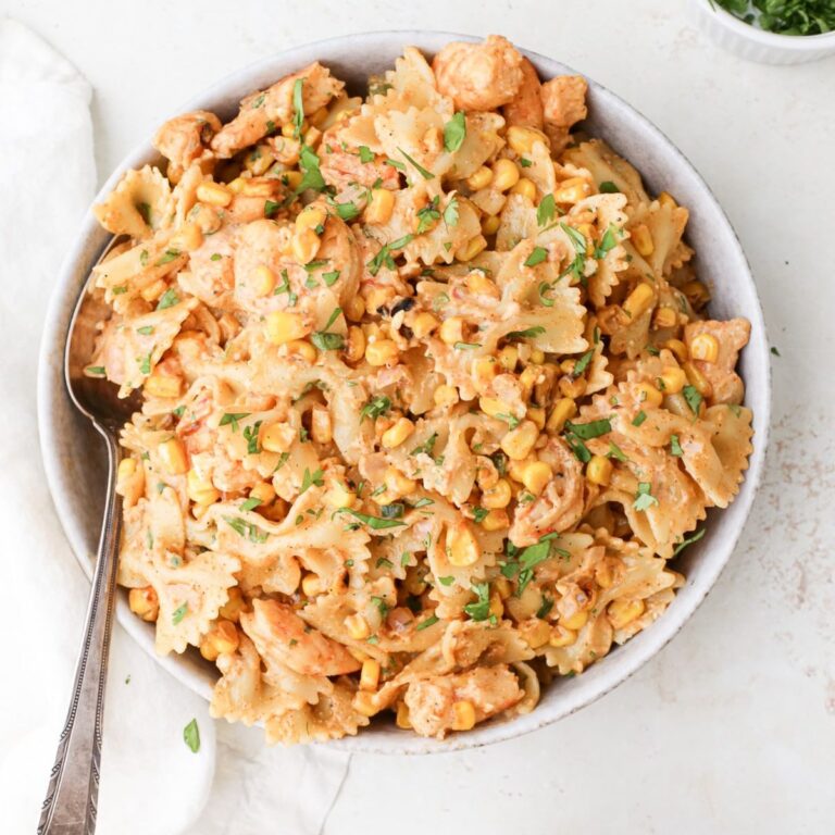 A large serving bowl of mexican street corn pasta salad with fresh cilantro and shrimp.