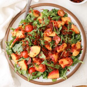 Peach salad with crispy prosciutto on a bed of arugula with cherry tomatoes and hot honey vinaigrette.