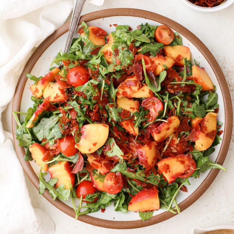 Peach salad with crispy prosciutto on a bed of arugula with cherry tomatoes and hot honey vinaigrette.