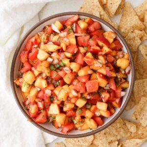 A bowl of homemade Trader Joe's smoky peach salsa served with tortilla chips.