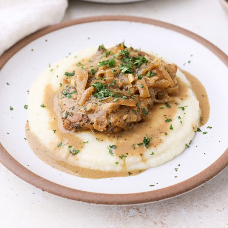 French onion chicken thighs on a bed of cauliflower mash with fresh parsley on top.