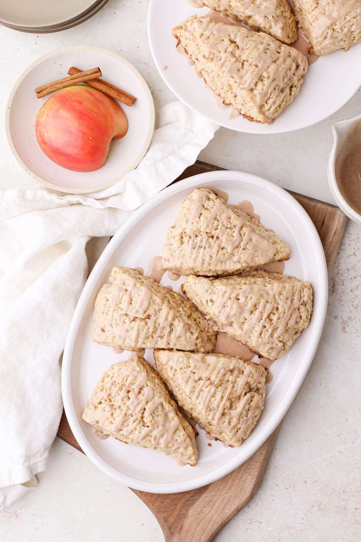 Homemade apple cinnamon scones with cinnamon glaze on an oval plate.