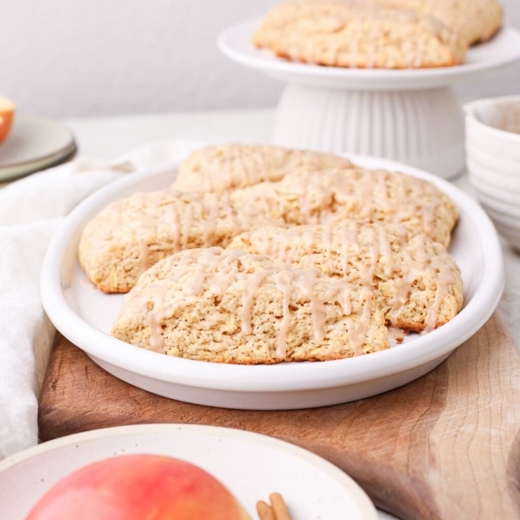 Homemade apple cinnamon scones with cinnamon glaze on an oval plate.