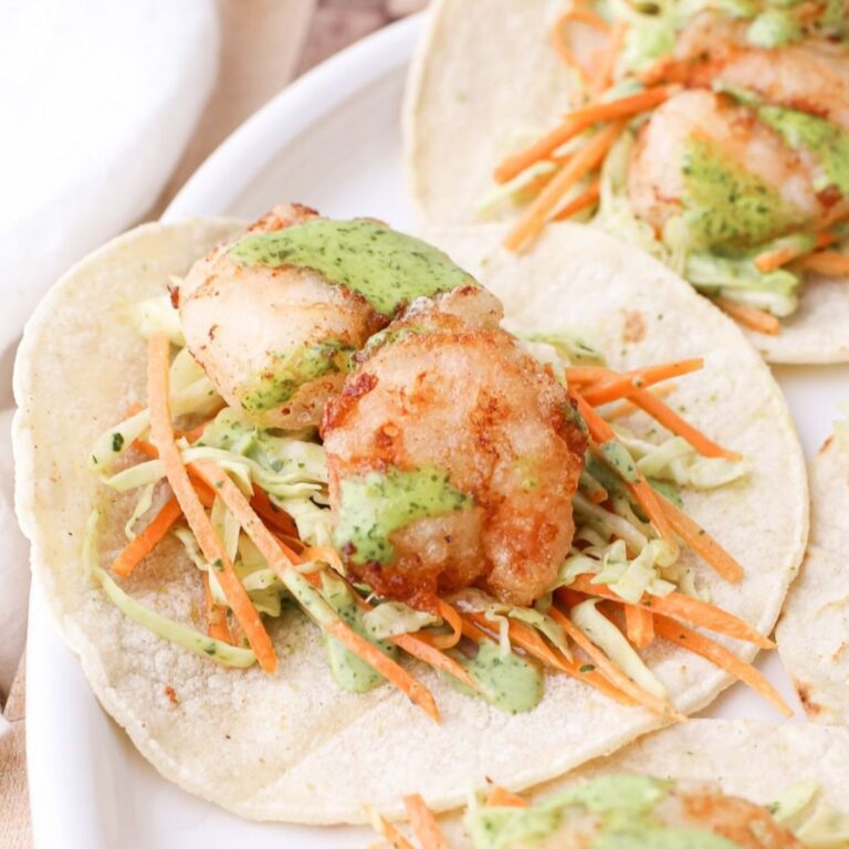 A plate of homemade crispy shrimp tacos with cilantro lime sauce.