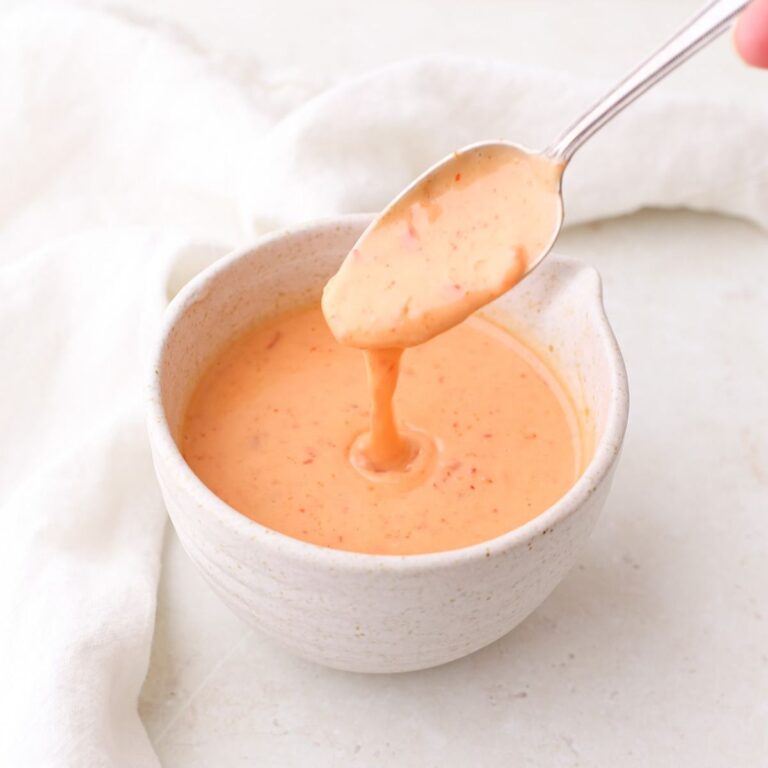 A bowl of homemade bang bang sauce with a spoonful dripping over the top.