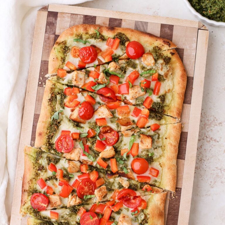 Homemade pesto chicken flatbread with cherry tomatoes and diced red bell pepper.