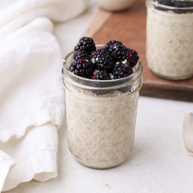 Two jars of dairy free high protein chia pudding topped with fresh blackberries and a sprinkle of hemp seeds.
