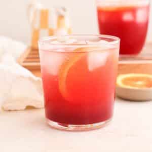 Two blood orange mocktails with hibiscus syrup, sparkling water, and ice cubes plus a blood orange slice.