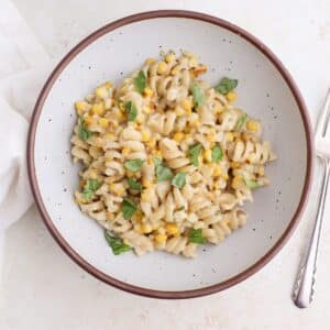 Two bowl of creamy corn pasta with fresh basil.