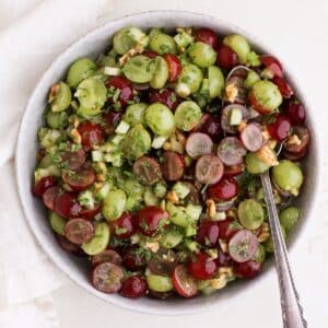 A serving bowl with tangy green and red grape salad with fresh mint and zesty citrus dressing (no cream cheese).
