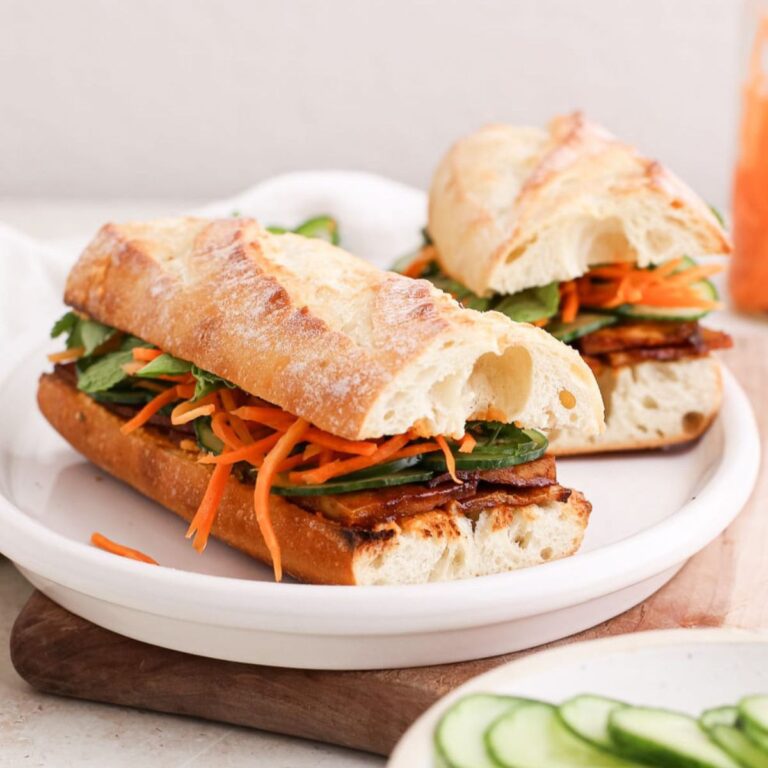 Tofu banh mi sandwiches with pickled carrots, thinly sliced cucumber, and fresh herbs.