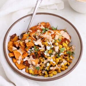 Street corn bowls with chicken and sweet potato topped with crumbled feta, cilantro, and drizzled with a creamy chili lime sauce.