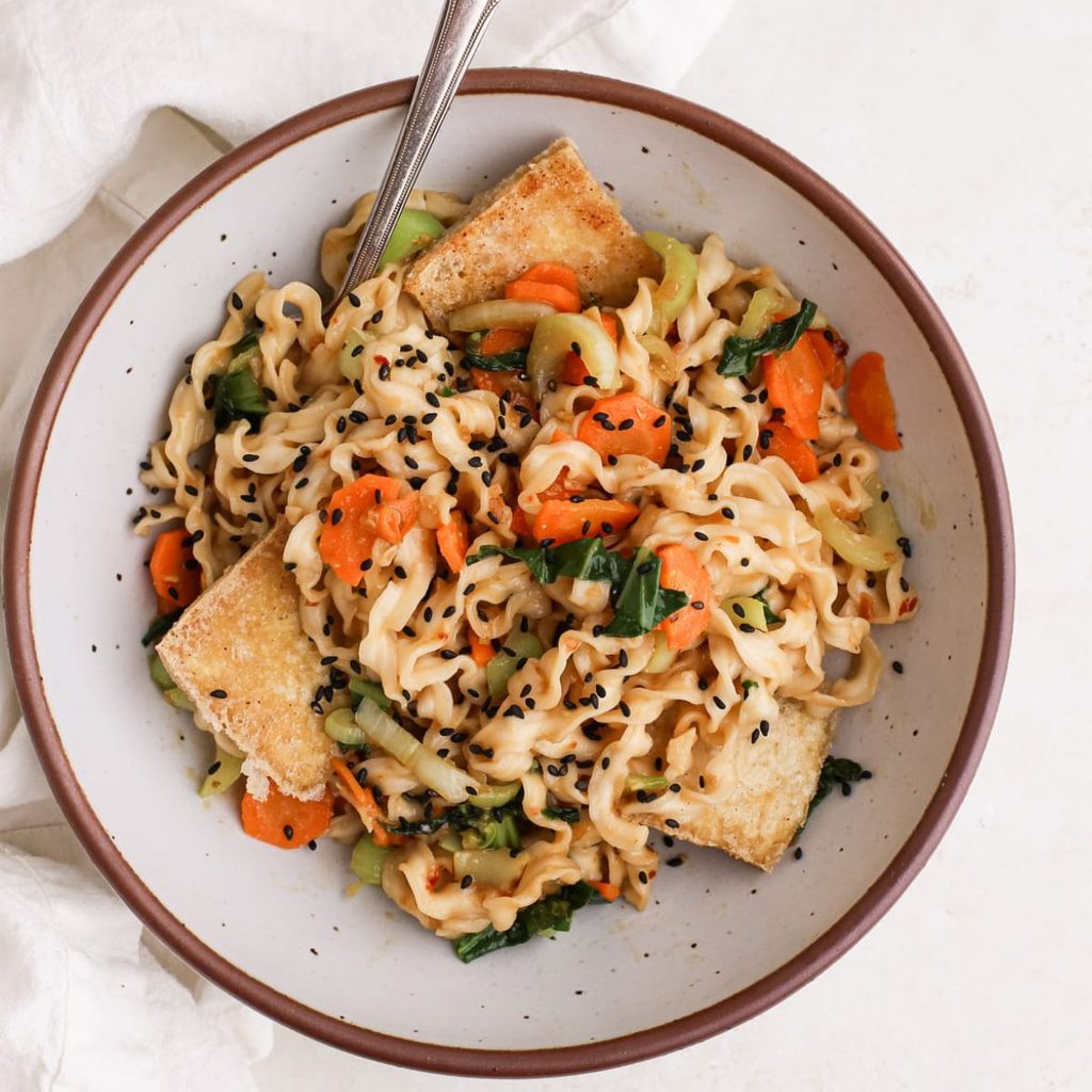 Miso noodles with crispy tofu, carrots, and bok choy, topped with black sesame seeds.
